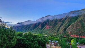 Soft morning fog drifts over the rugged mountains near Ami’s Campground, with the first light of sunrise casting a subtle glow on the peaks.