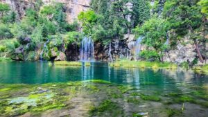 Multiple waterfalls pour over rocky ledges at Hanging Lake, their flowing streams creating a dynamic contrast against the rugged canyon walls.